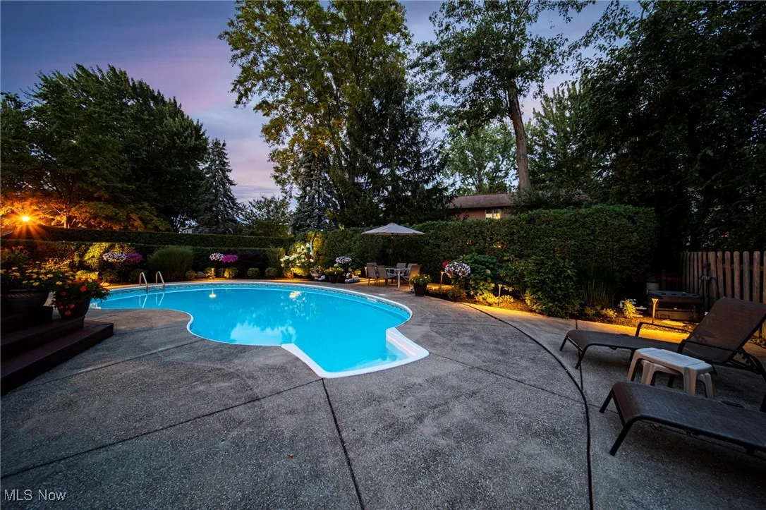 Pool at dusk with a fenced backyard and a patio area