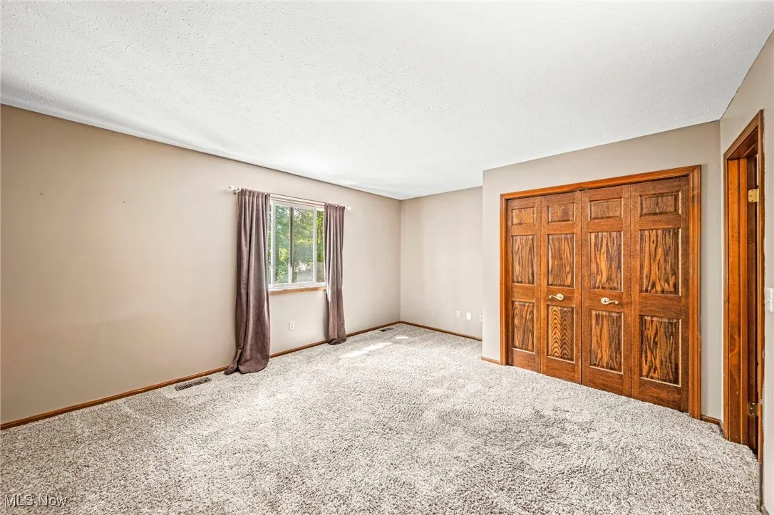 Unfurnished bedroom with a textured ceiling, a closet, and carpet