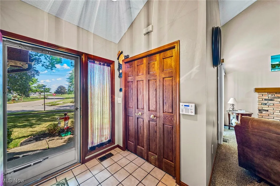 Foyer featuring light tile patterned floors and light colored carpet