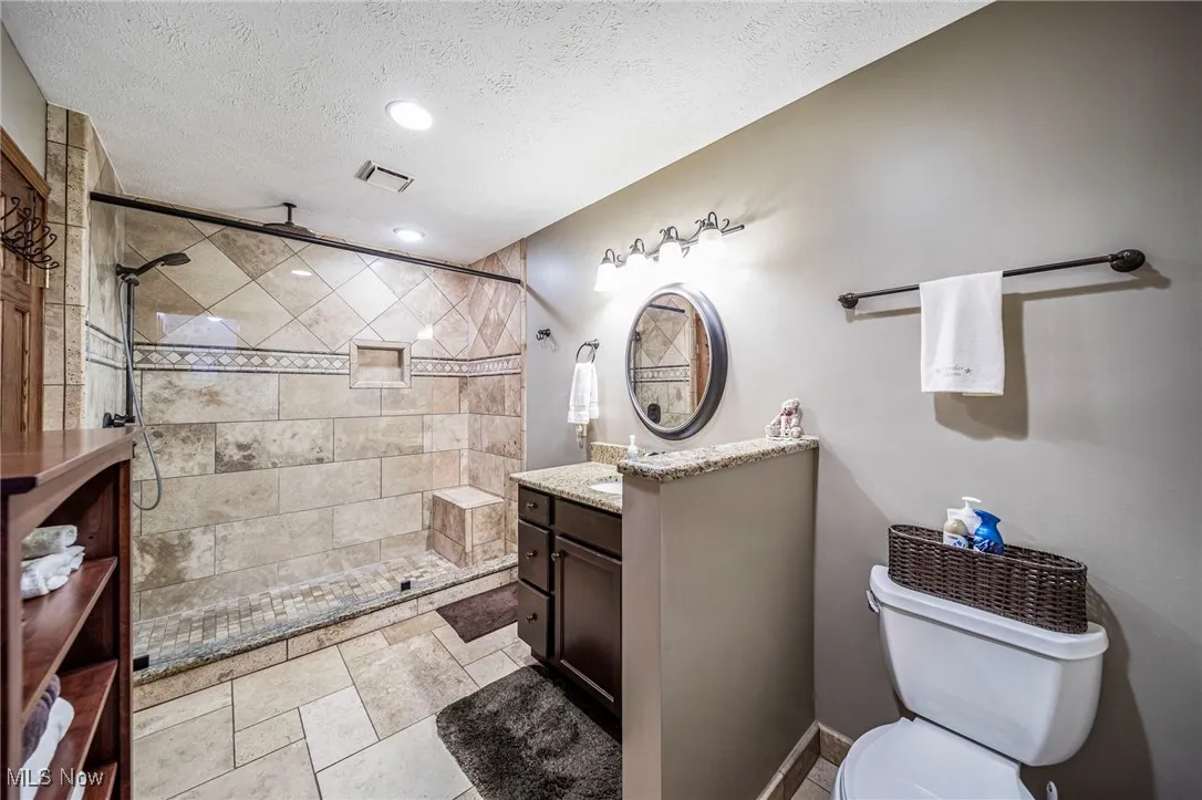 Bathroom with vanity, a textured ceiling, a stall shower, and recessed lighting