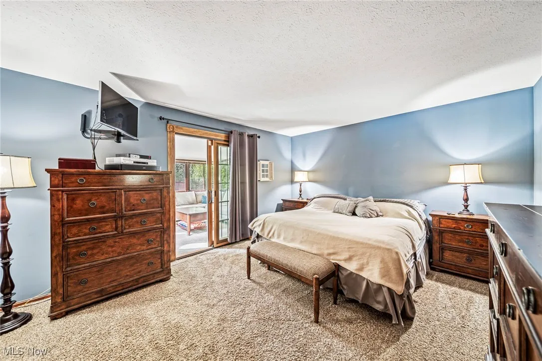 Bedroom featuring light carpet, access to exterior, and a textured ceiling