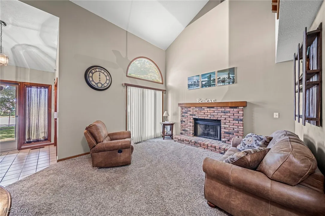 Tiled living room with high vaulted ceiling, carpet floors, and a fireplace