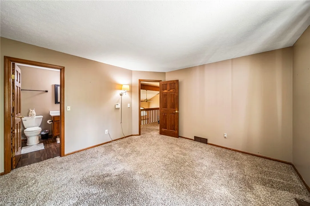 Unfurnished bedroom with carpet flooring and ensuite bathroom