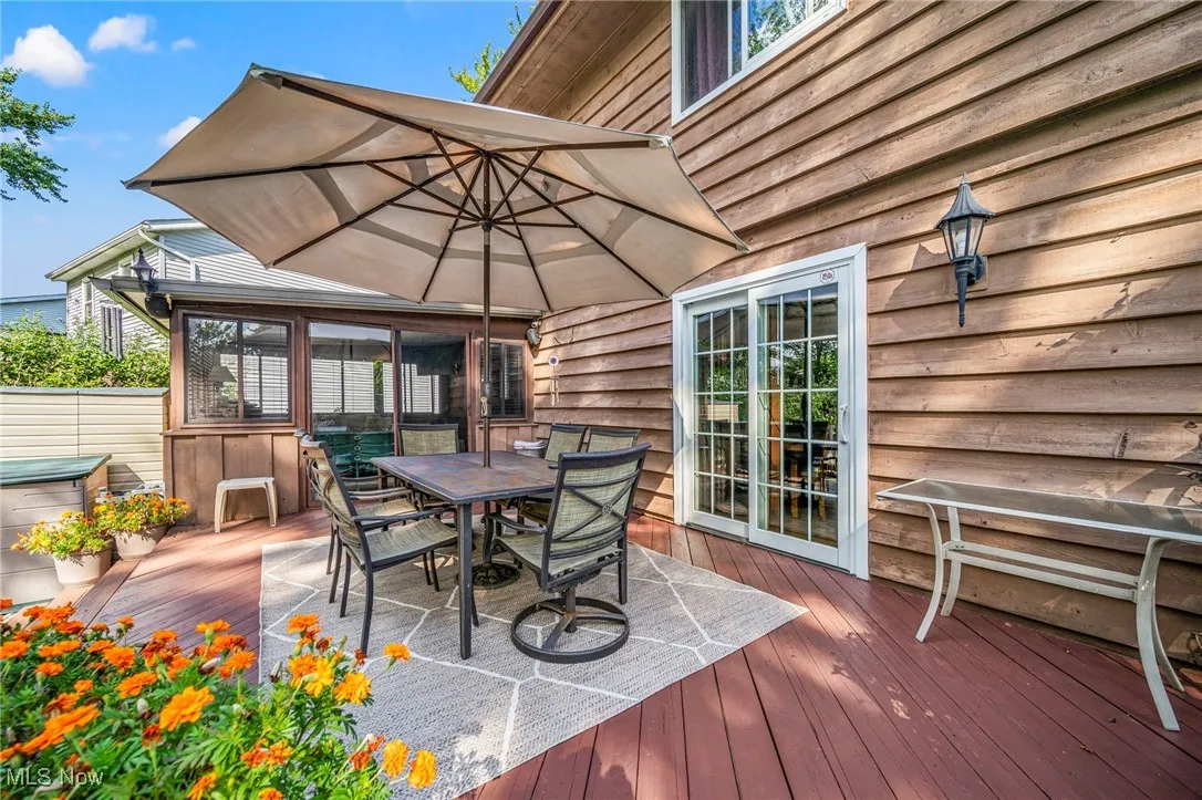 Deck featuring a sunroom, outdoor dining space, and a hot tub