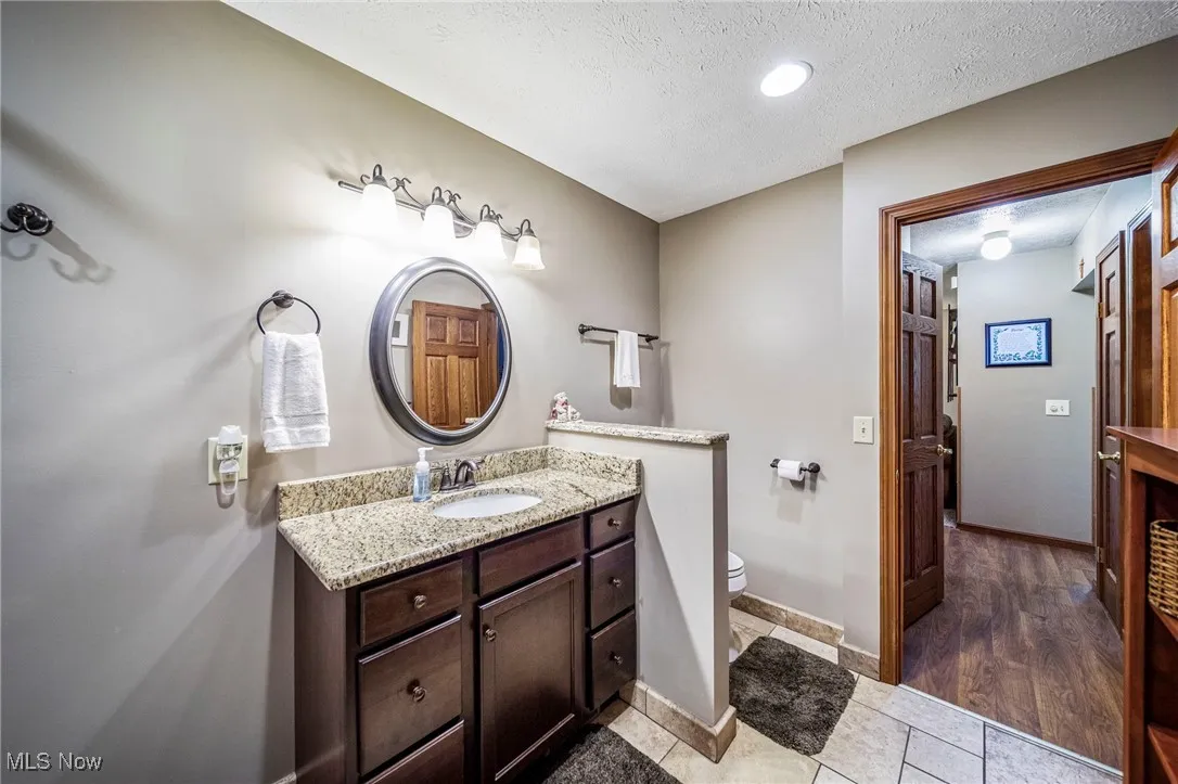 Bathroom featuring vanity, a textured ceiling, light tile patterned floors, and recessed lighting