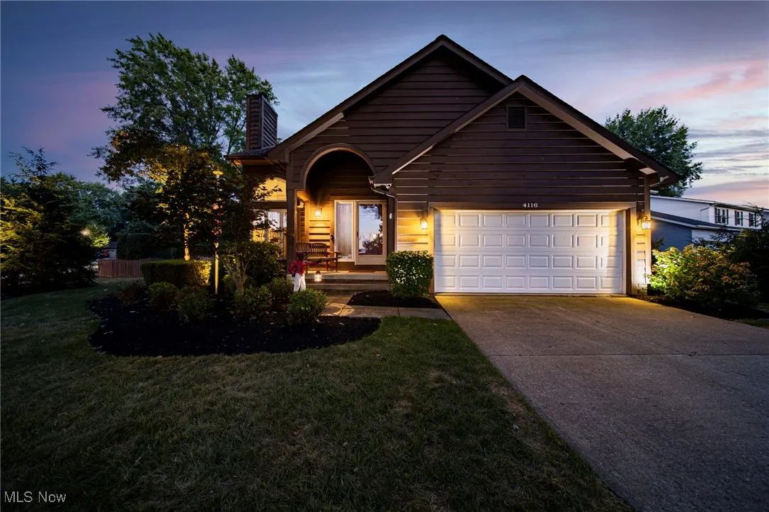 View of front facade with driveway, a chimney, an attached garage, and a front yard