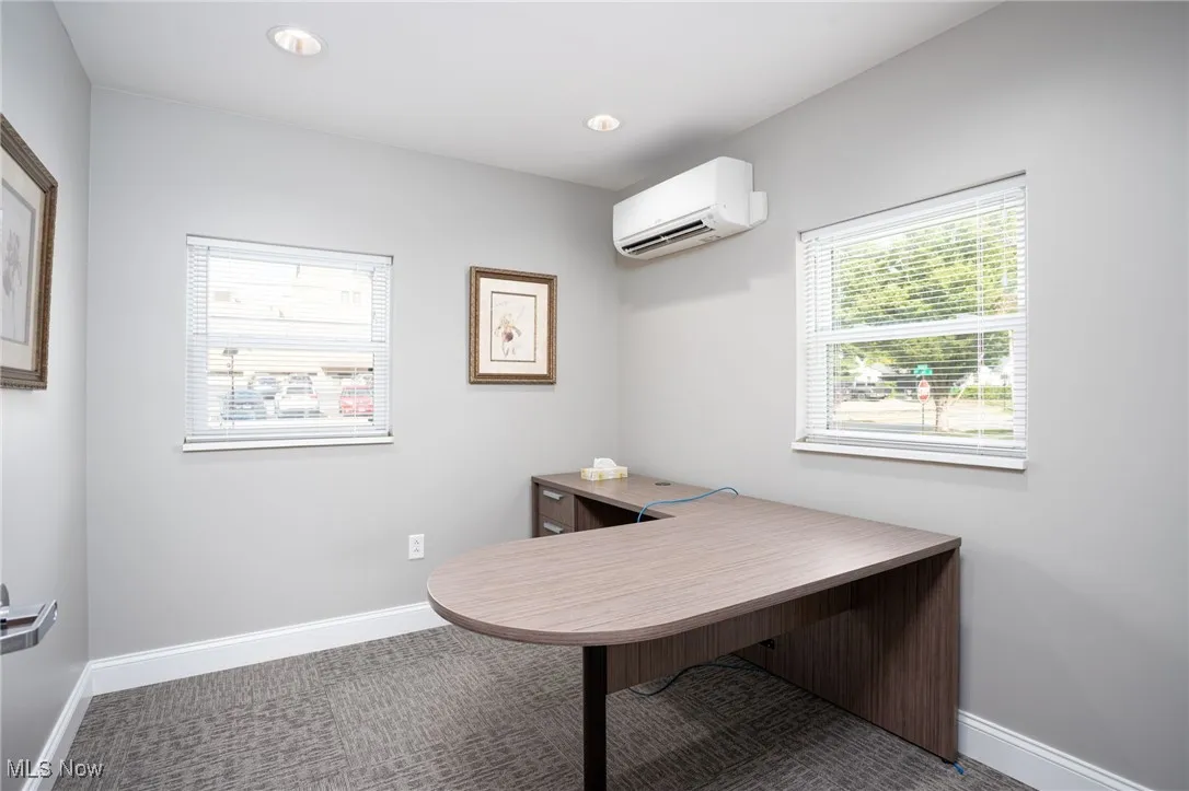 Office area featuring carpet, an AC wall unit, and recessed lighting