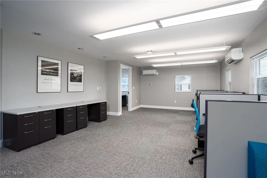 Unfurnished office featuring light colored carpet and a wall mounted AC