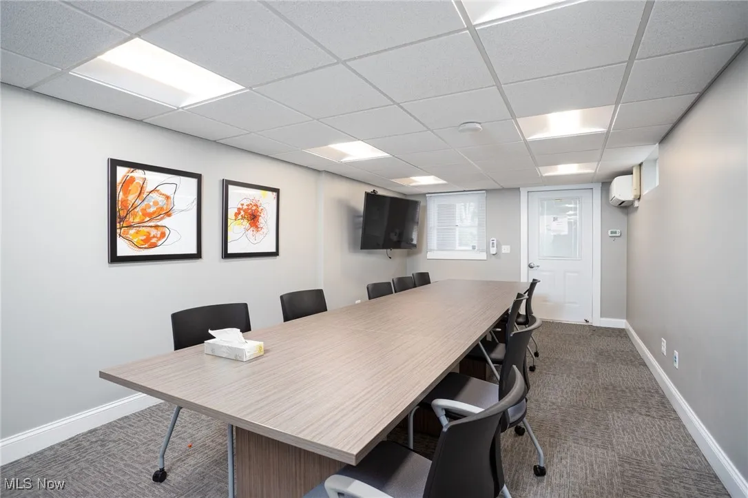 Office area with carpet, a drop ceiling, and an AC wall unit