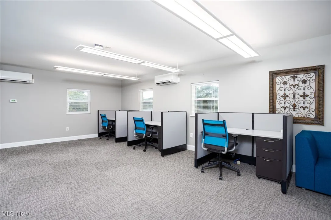Office space with light carpet and a wall unit AC