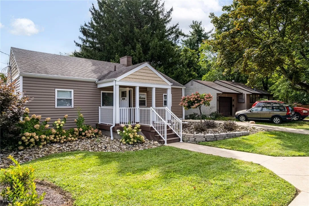 Ranch-style home featuring covered porch, roof with shingles, a front yard, and a chimney