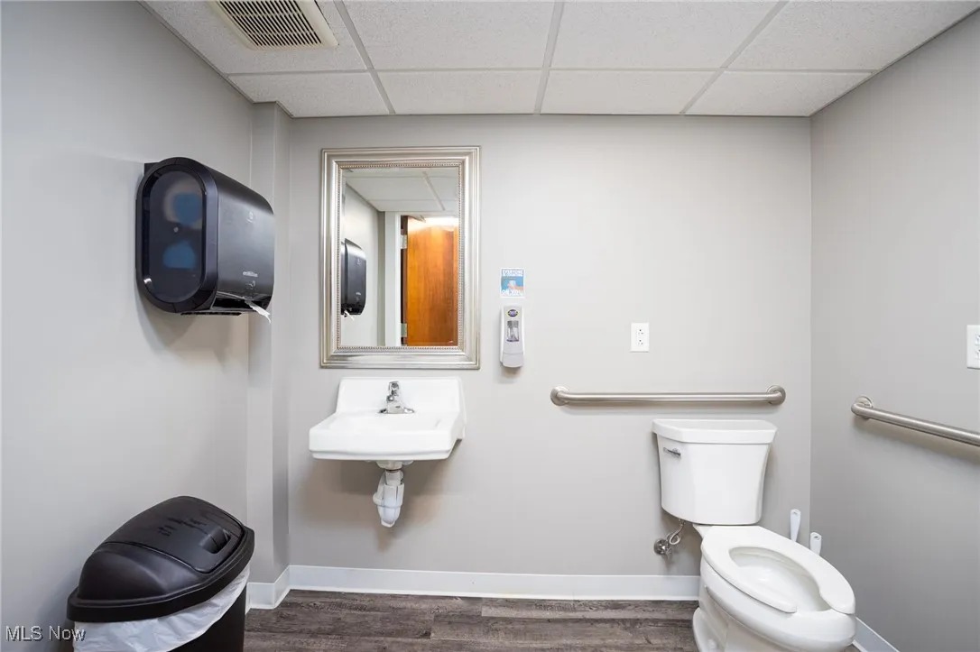 Bathroom featuring dark wood-style flooring and a drop ceiling