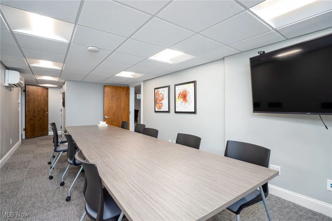 Office area with a paneled ceiling, light colored carpet, and a wall unit AC