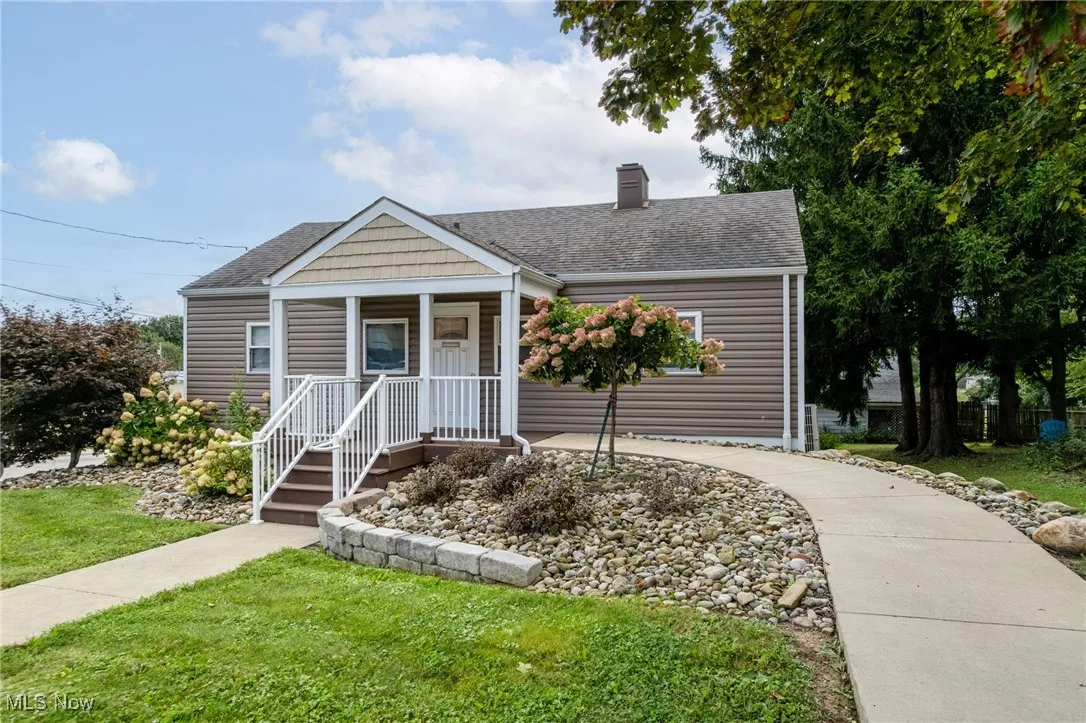 View of front facade with a porch, a shingled roof, a front yard, and a chimney