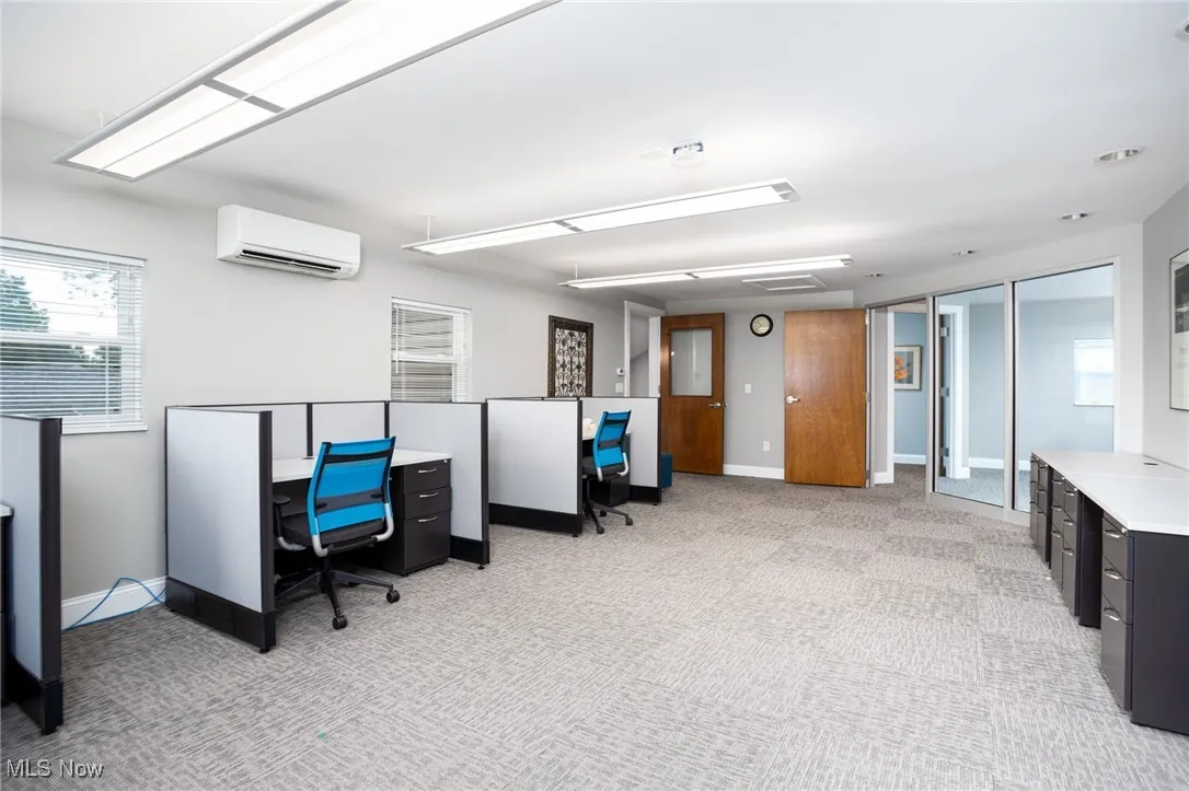 Home office with light carpet and a wall mounted air conditioner