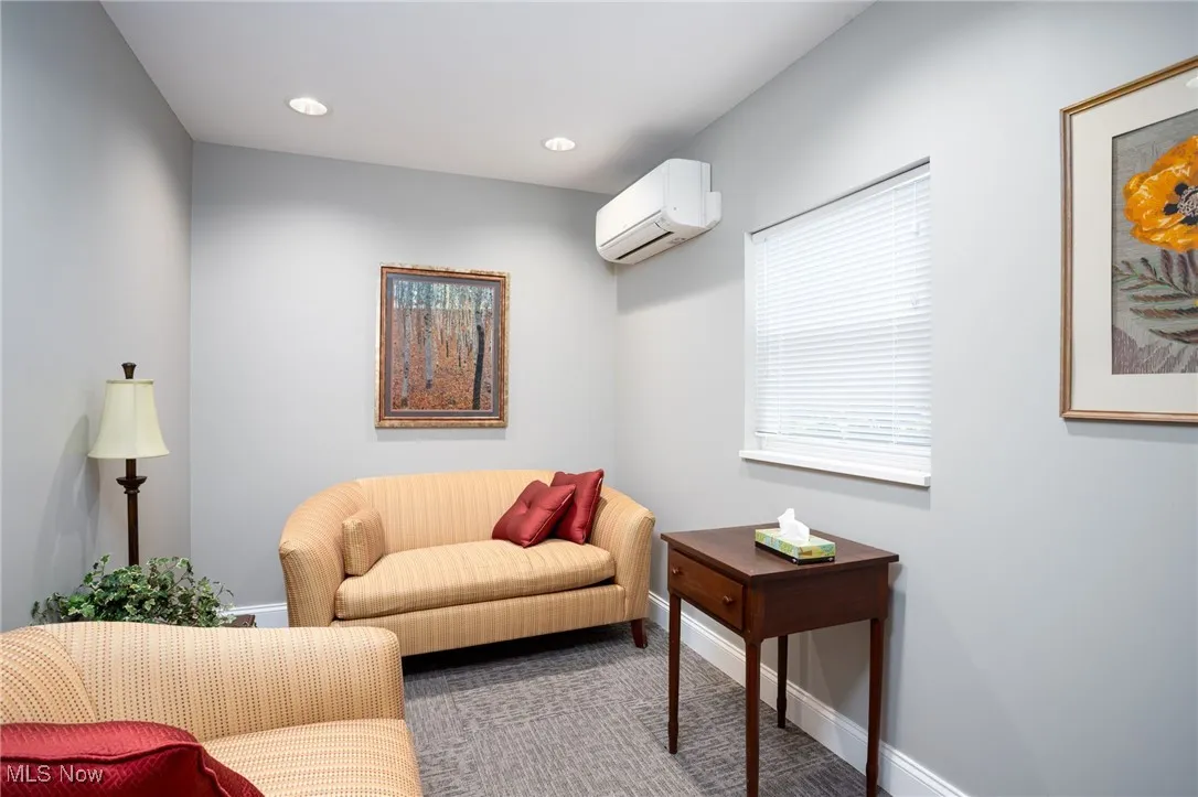 Living room with a wall mounted air conditioner, recessed lighting, and carpet floors