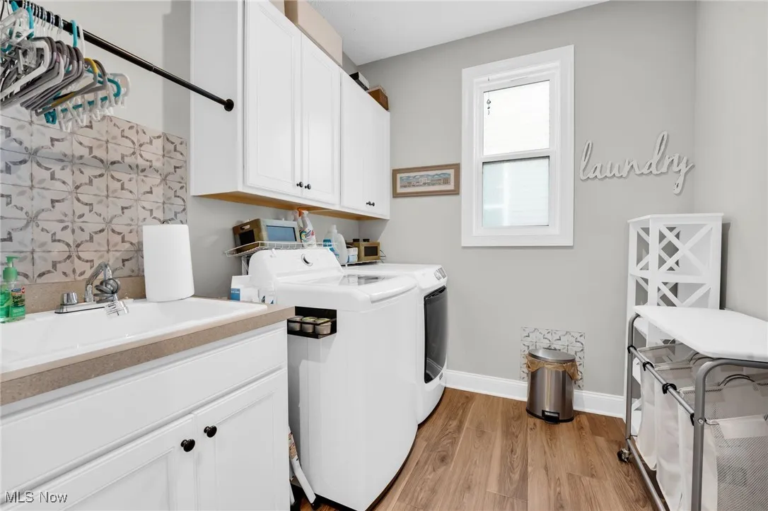 Laundry area featuring wood finished floors, washing machine and dryer, and cabinet space