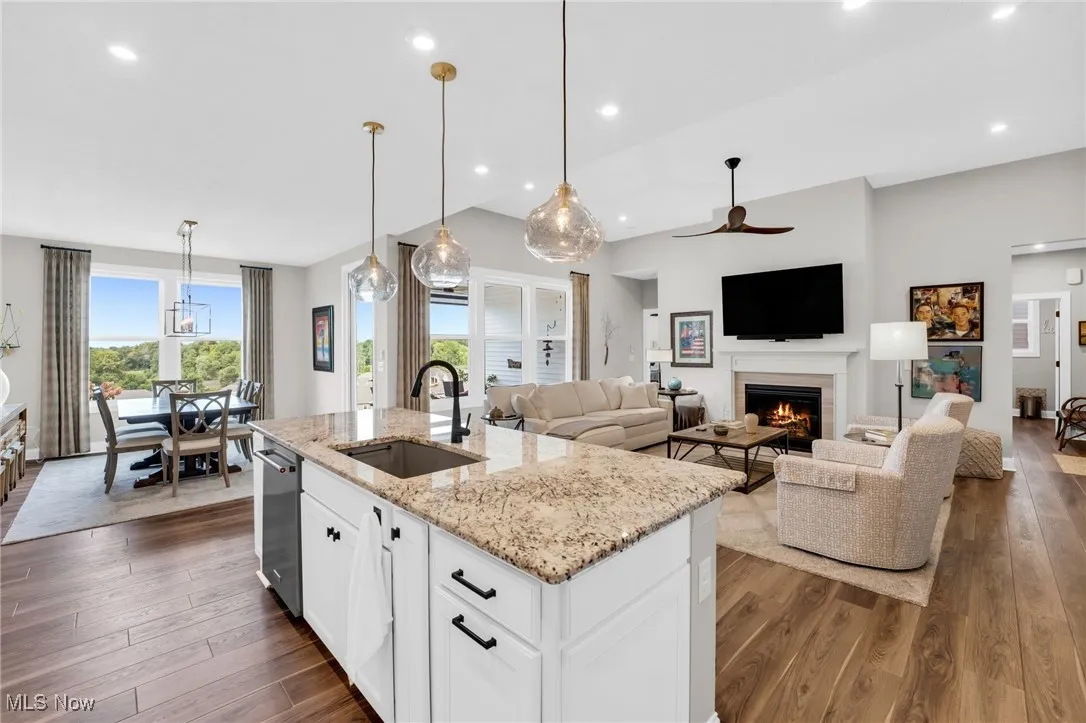 Kitchen with white cabinets, light stone countertops, pendant lighting, recessed lighting, and a lit fireplace