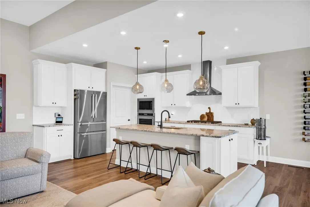 Kitchen featuring light stone counters, stainless steel appliances, open floor plan, dark wood-style flooring, and recessed lighting