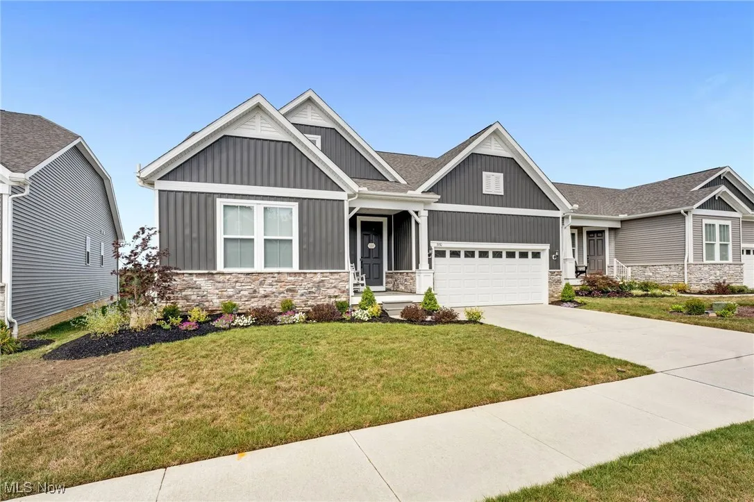 Craftsman-style home featuring stone siding, a front yard, driveway, board and batten siding, and a garage