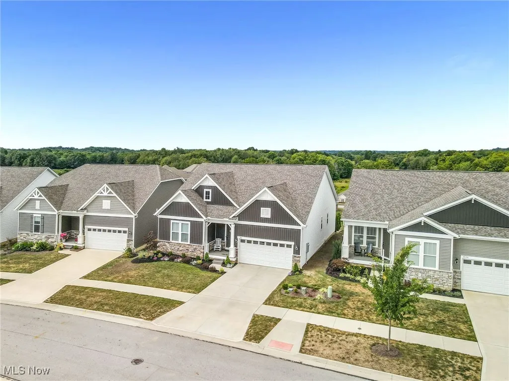 Craftsman-style house with stone siding, a shingled roof, and driveway