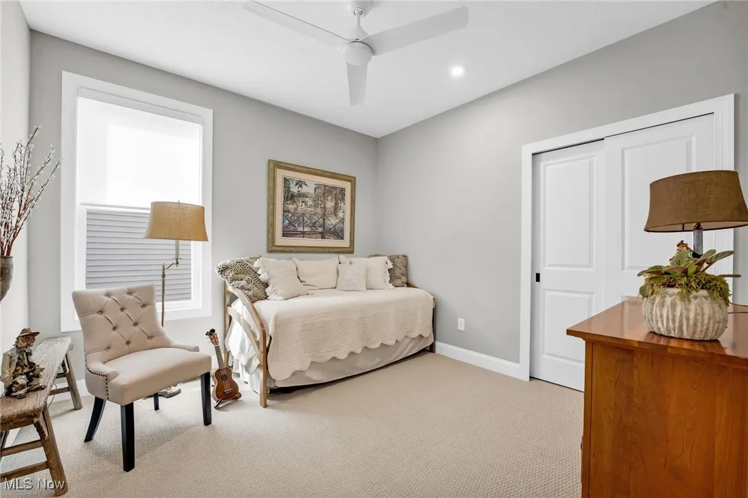 Bedroom featuring light carpet, a ceiling fan, and a closet
