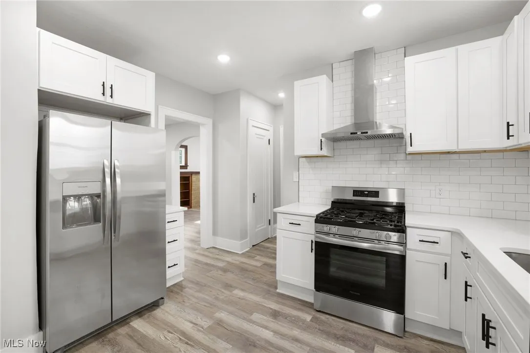 Kitchen with white cabinets, LVT floors, and stainless-steel appliances