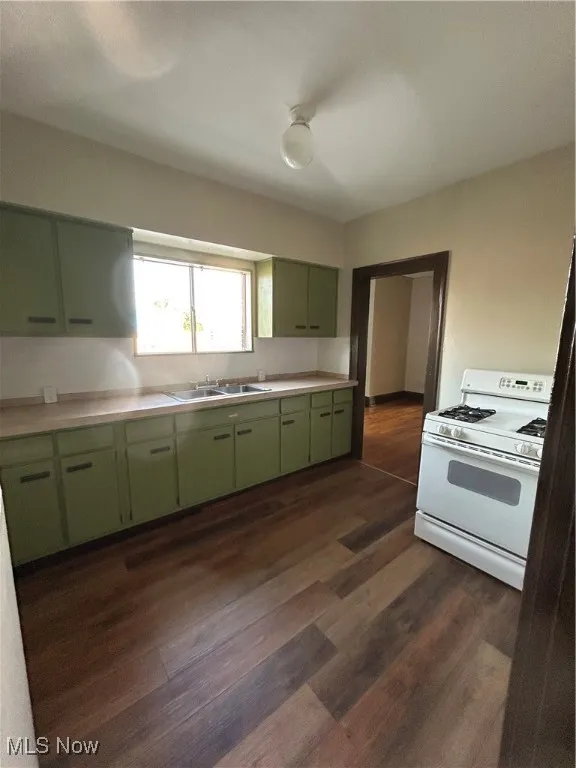 Kitchen featuring green cabinets, light countertops, range, and dark wood finished floors