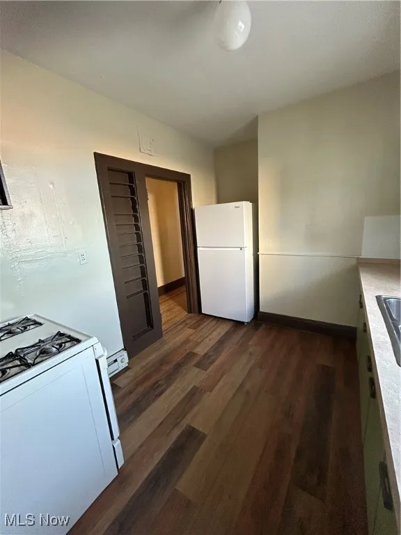 Kitchen featuring stove, dark wood-style floors, white fridge, and light countertops