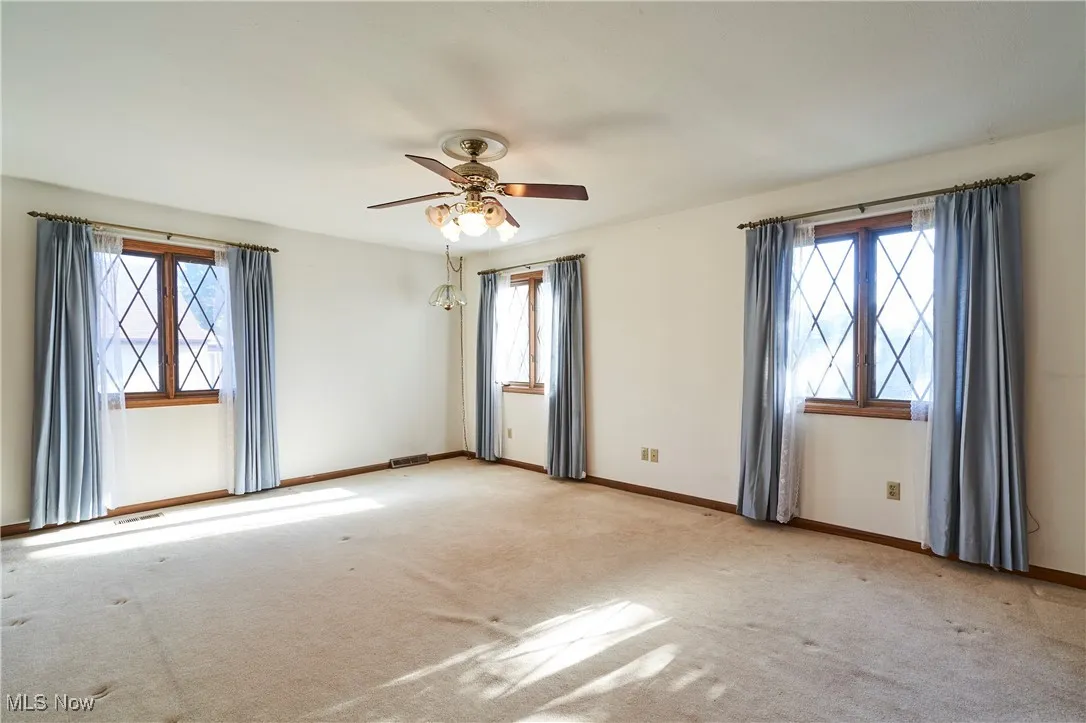 Large master bedroom with ceiling fan and carpet