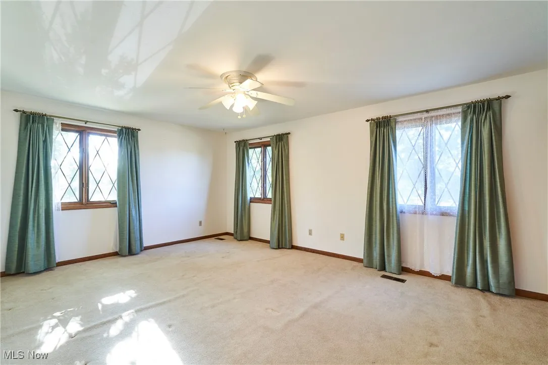 Bedroom  featuring healthy amount of natural light, light colored carpet, and a ceiling fan