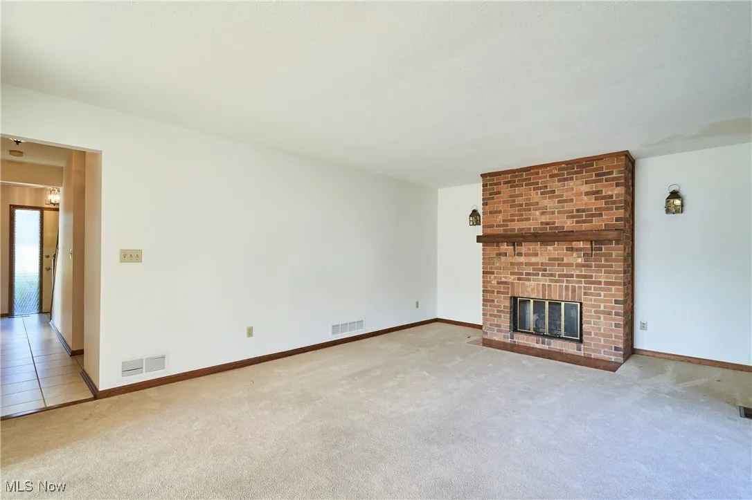 Living room with a brick fireplace and carpet floors