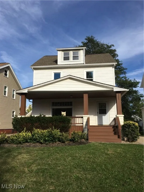 Traditional style home featuring covered porch and a front lawn