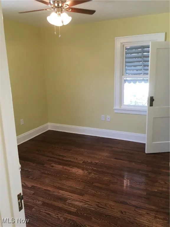 Unfurnished room with dark wood-type flooring and ceiling fan