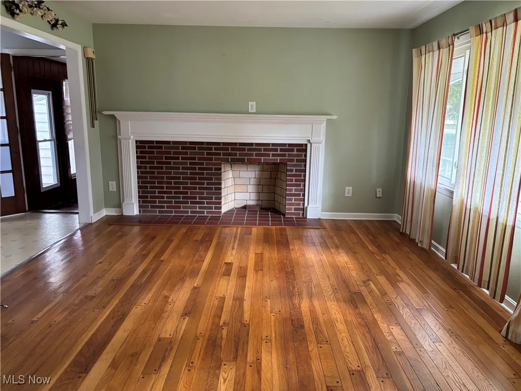Unfurnished living room with dark wood-style floors and a fireplace with flush hearth