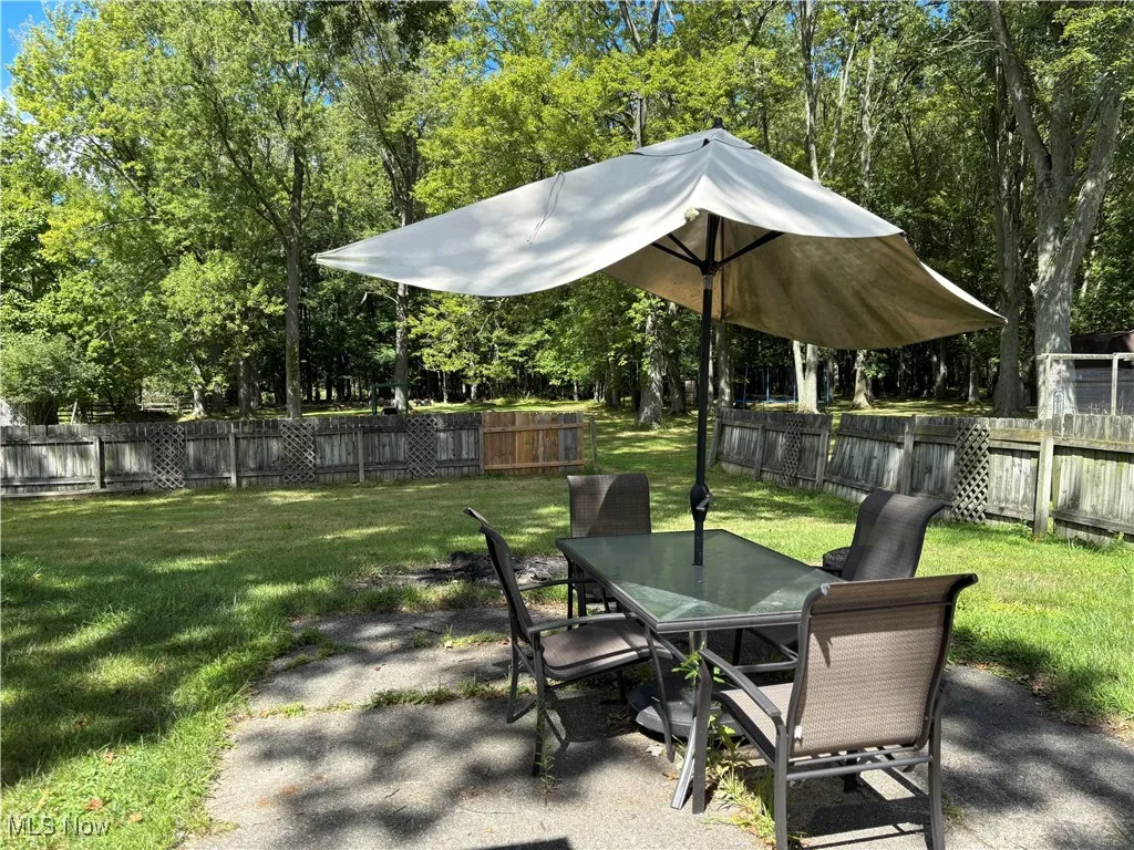 Fenced backyard with outdoor dining area, a patio area, and view of wooded area