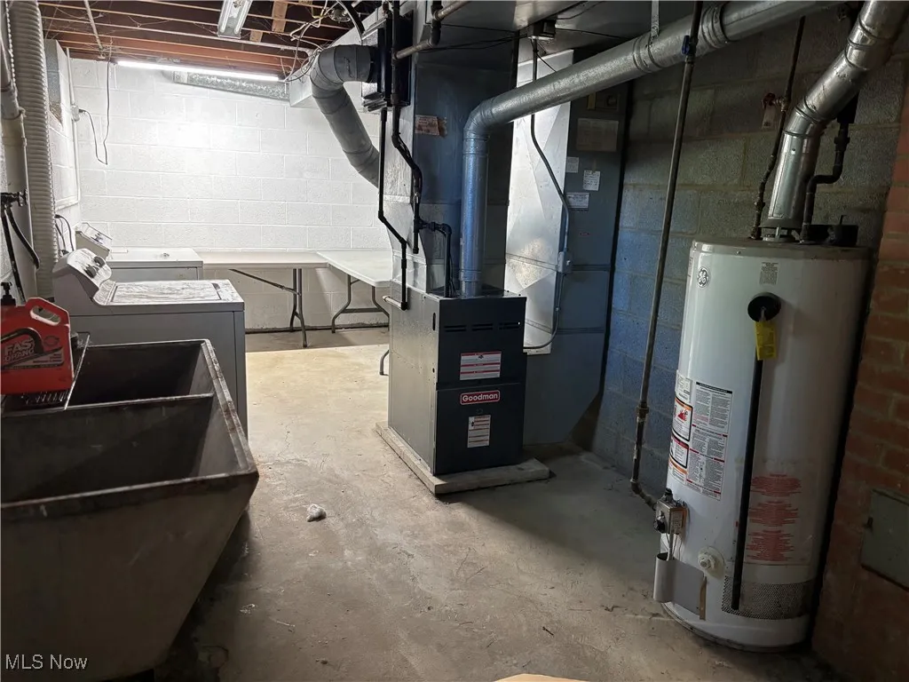 Unfinished below grade area featuring water heater and heating unit