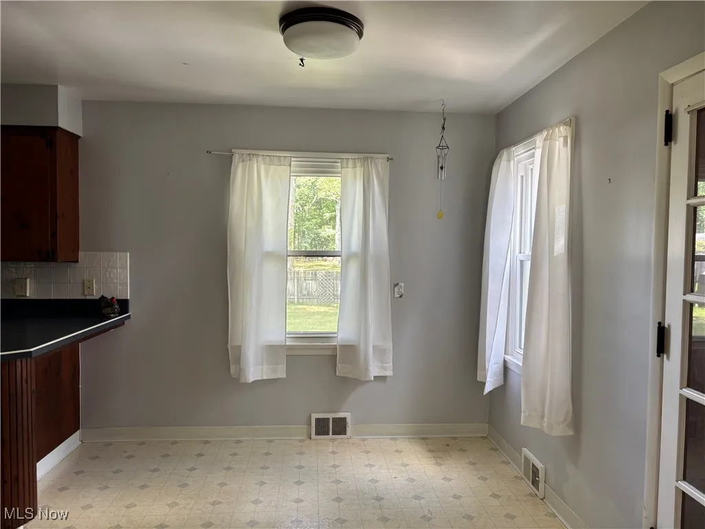 Unfurnished dining area featuring light floors and baseboards
