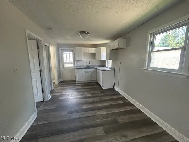 Kitchen featuring white cabinetry, a textured ceiling, and dark wood-style floors