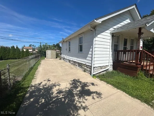 View of side of home featuring a storage unit and driveway