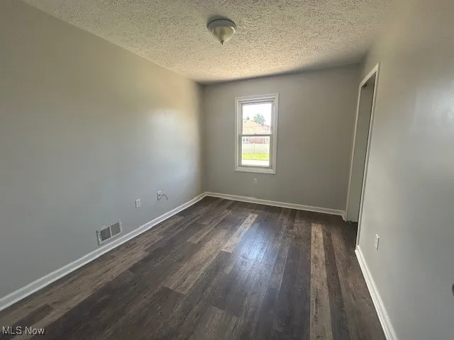 Bedroom with a textured ceiling and dark wood finished floors