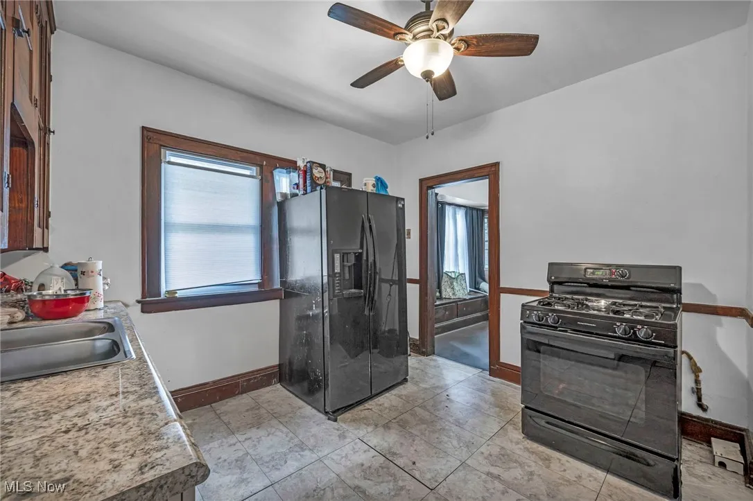 Kitchen featuring black appliances, a ceiling fan, light countertops, and light tile patterned floors