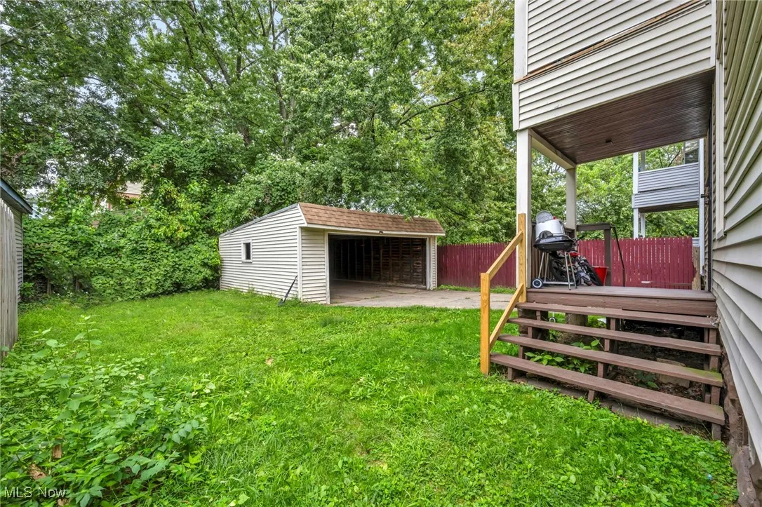 View of yard with an outbuilding, a patio, a garage, view of scattered trees, and a deck