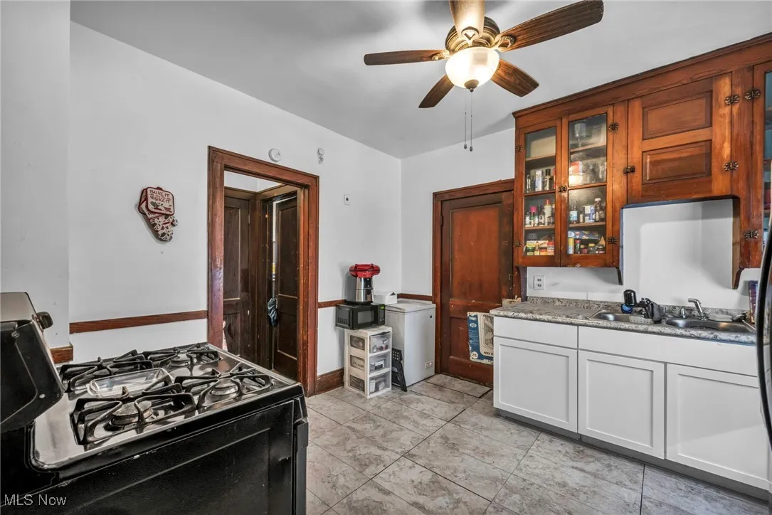 Kitchen featuring black appliances, glass insert cabinets, a ceiling fan, and light tile patterned floors