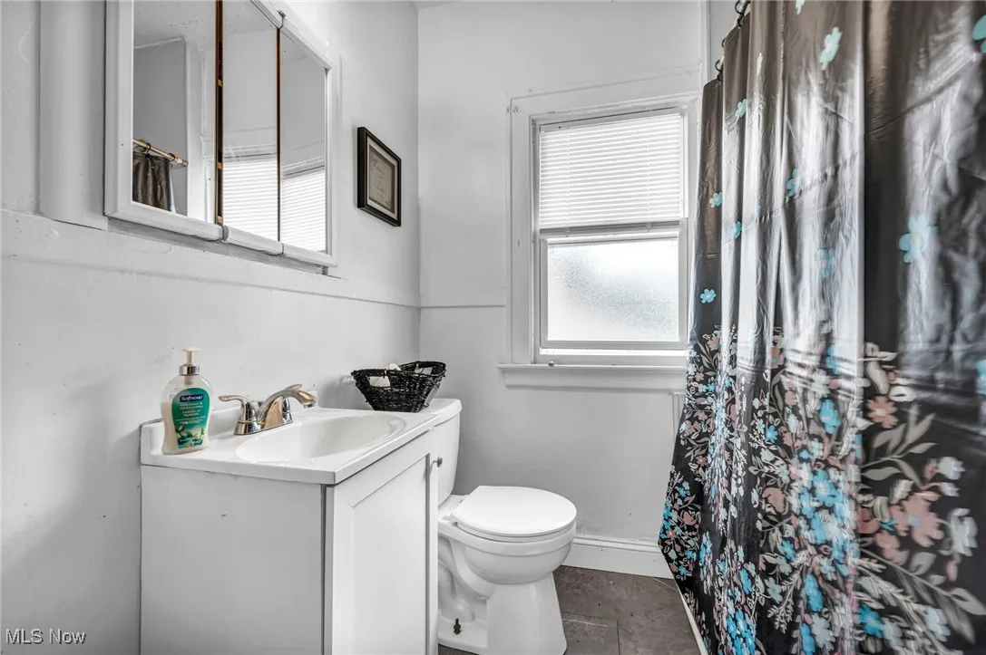 Full bath with vanity, curtained shower, and dark tile patterned flooring