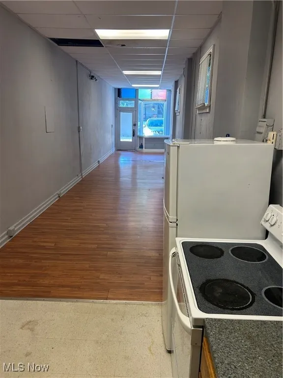 Kitchen with range, a paneled ceiling, light flooring, and stainless steel fridge