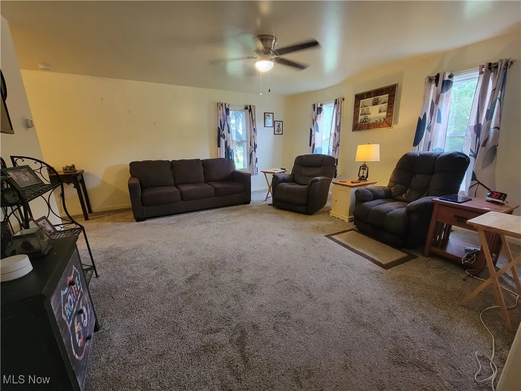 Carpeted living room with ceiling fan