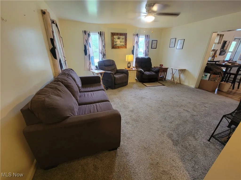 Carpeted living room featuring baseboards and ceiling fan