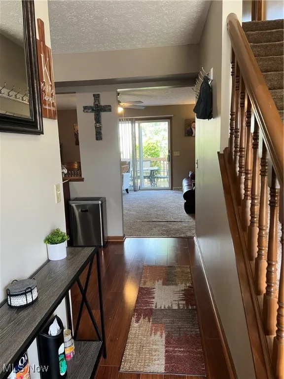 Foyer entry featuring a textured ceiling, dark laminate floors and stairs