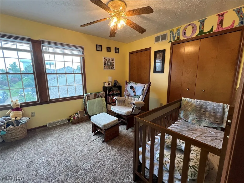 Carpeted bedroom featuring two closets, a textured ceiling with a fan
